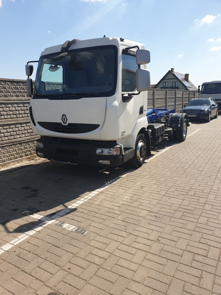 Biała kabina samochodu ciężarowego Renault bez zabudowy na placu z kostki brukowej, widoczny fragment ramy i podwozia.