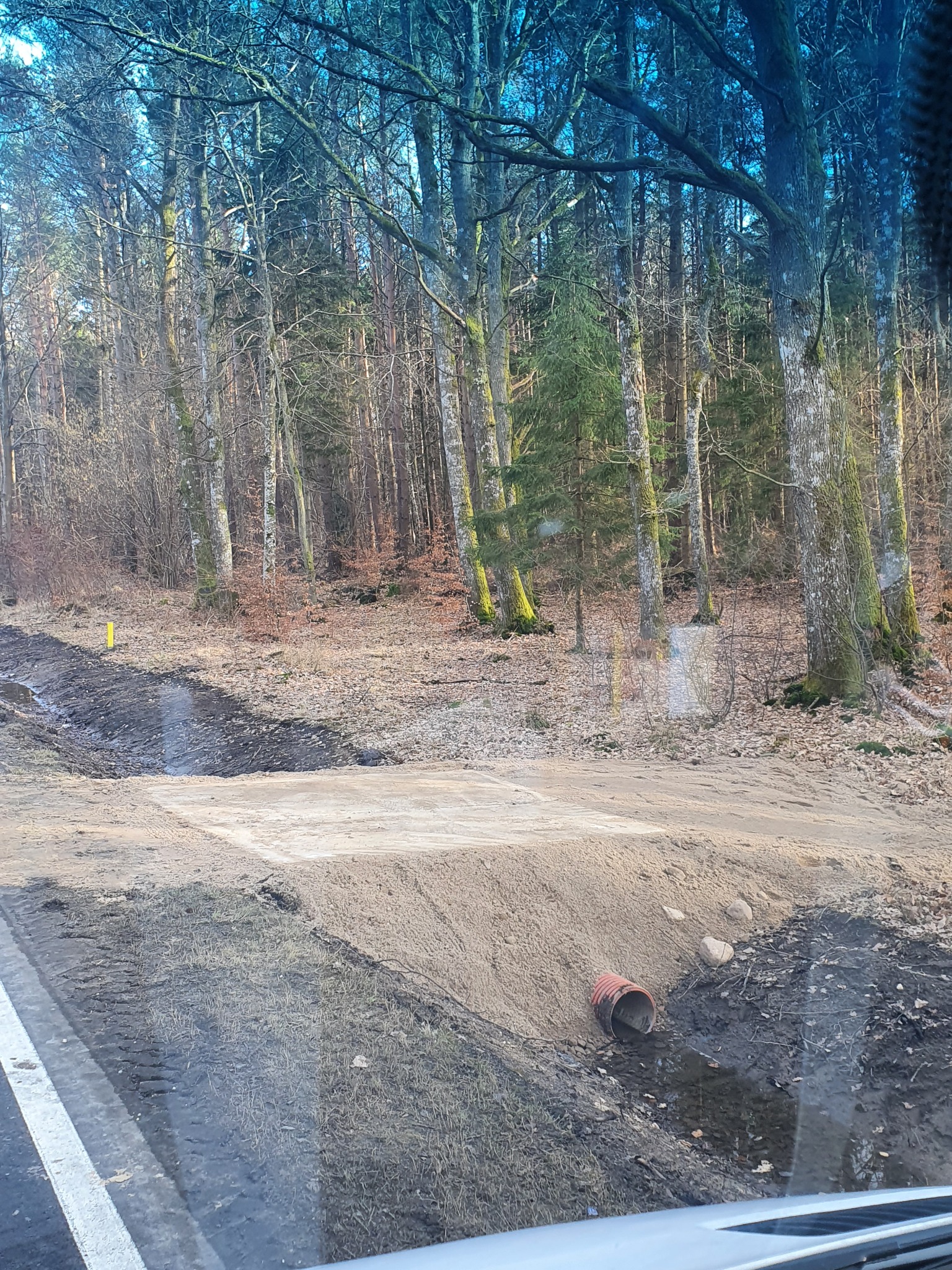 Wykonany przepust wodny pod drogą gruntową w lesie, widoczna rura drenażowa w wykopie.