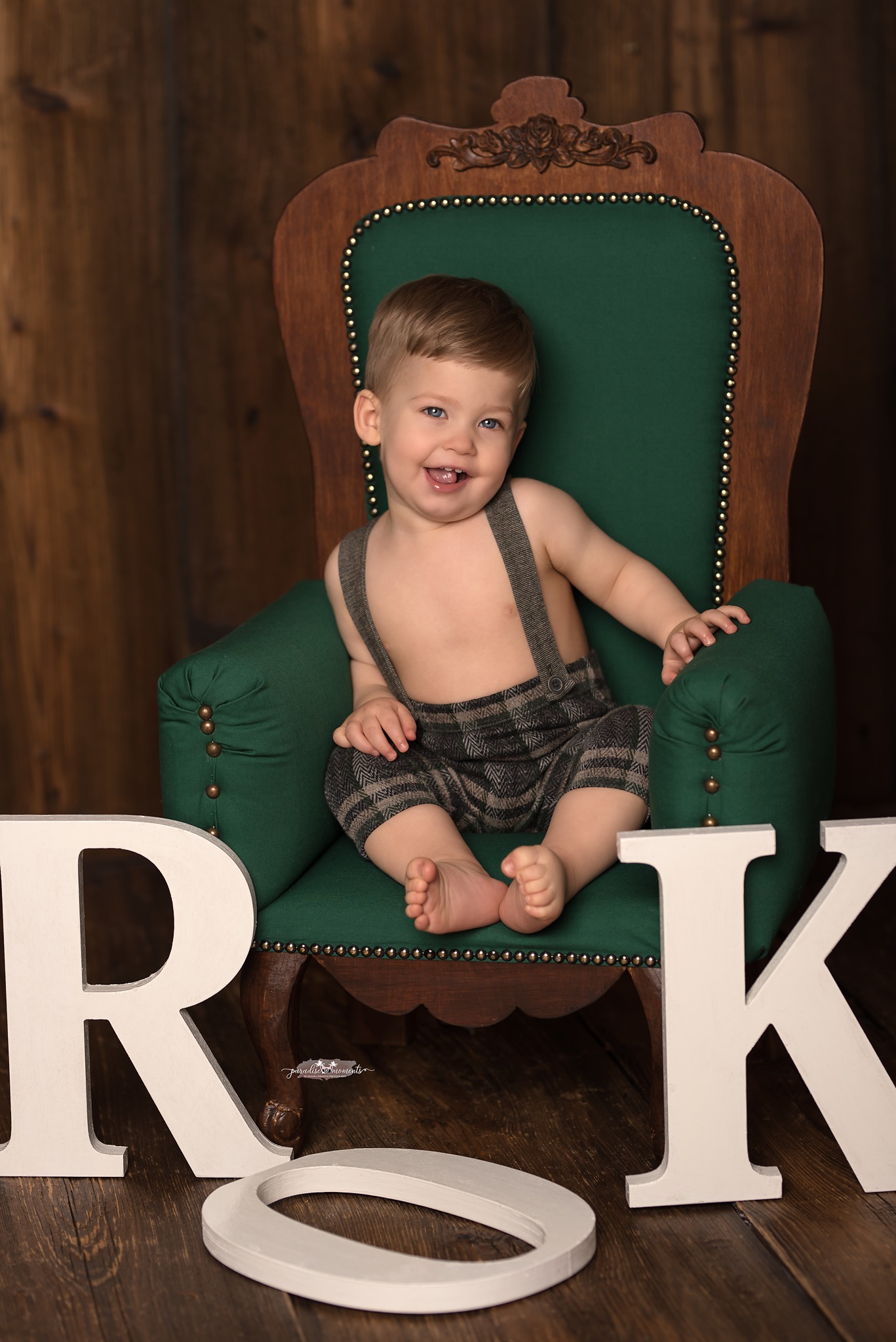 Uśmiechnięty chłopiec w szelkach i krótkich spodniach siedzi na zielonym fotelu z dekoracyjnymi literami 'ROK' na podłodze, Rzeszów.