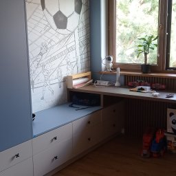 Parago Meble Tomasz Hańczaruk - Niebiesko-biała szafa z szufladami i blatem roboczym w pokoju dziecięcym z motywem piłkarskim na ścianie i zabawkami na blacie.