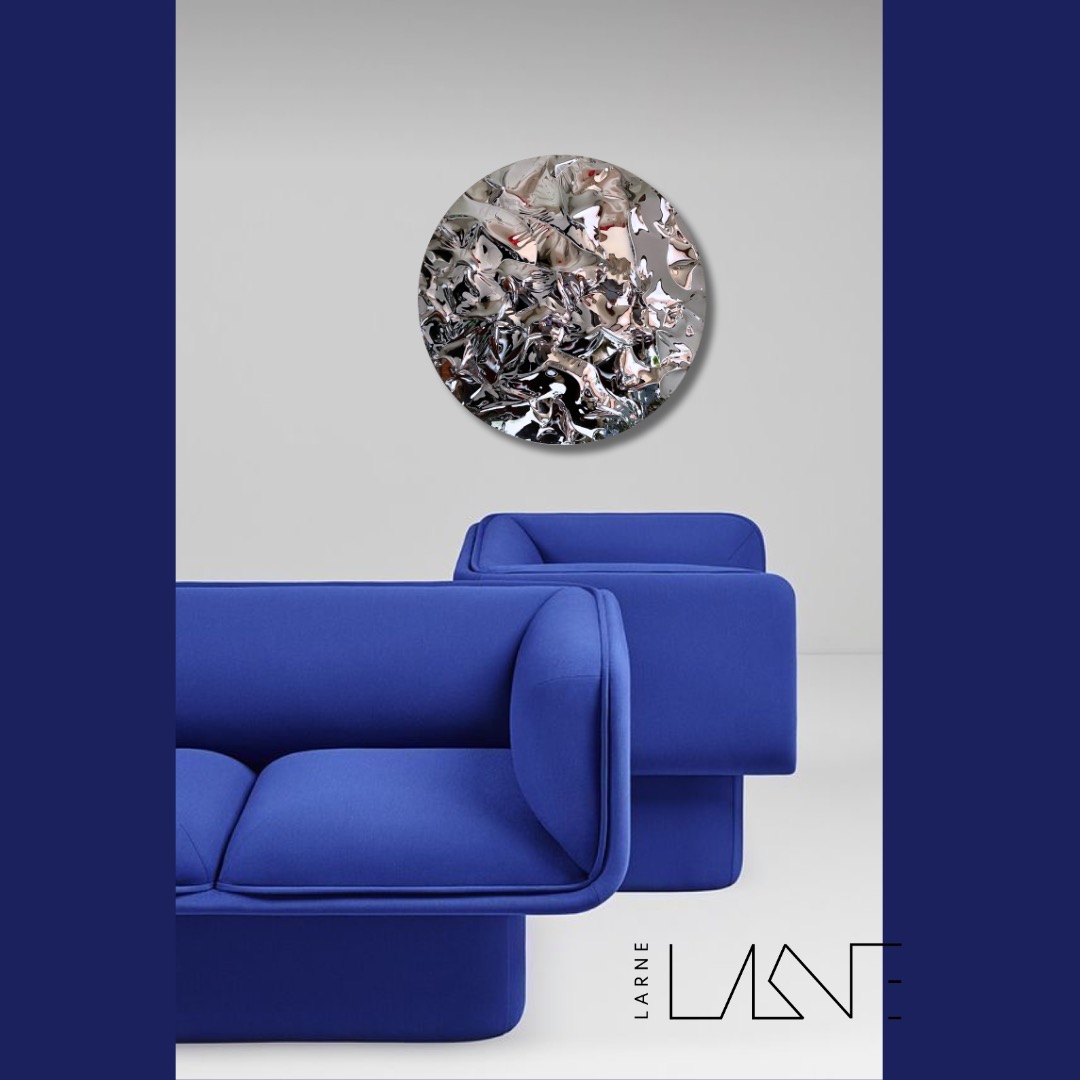 Stylowe, kobaltowe sofy w nowoczesnym wnętrzu z okrągłą, srebrną dekoracją ścienną. Minimalistyczny design, podkreślony przez czysty, biały plan i logo w rogu.