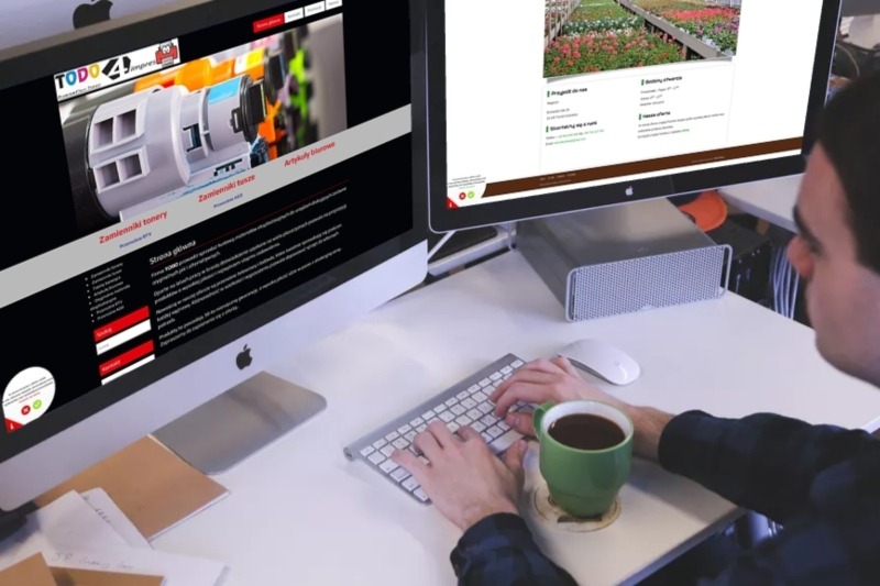Osoba pracuje na dwóch monitorach Apple, na jednym widoczna strona internetowa z ofertą zamienników tonerów, na drugim strona z kwiatami, obok klawiatury stoi zielony kubek z kawą.