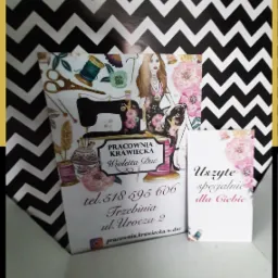 Dwie wizytówki pracowni krawieckiej Wioletta Duc na tle czarno-białego zygzakowatego wzoru. Jedna wizytówka z ilustracjami maszyny do szycia, szpul, nożyczek i portretu kobiety, zawiera dane...