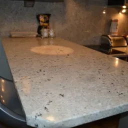 Jasny, nakrapiany blat z kamienia w kuchni w Gryficach, z widocznym fragmentem barku i wyposażeniem kuchennym w tle.