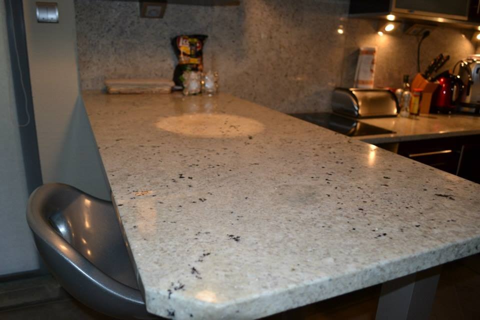 Jasny, nakrapiany blat z kamienia w kuchni w Gryficach, z widocznym fragmentem barku i wyposażeniem kuchennym w tle.