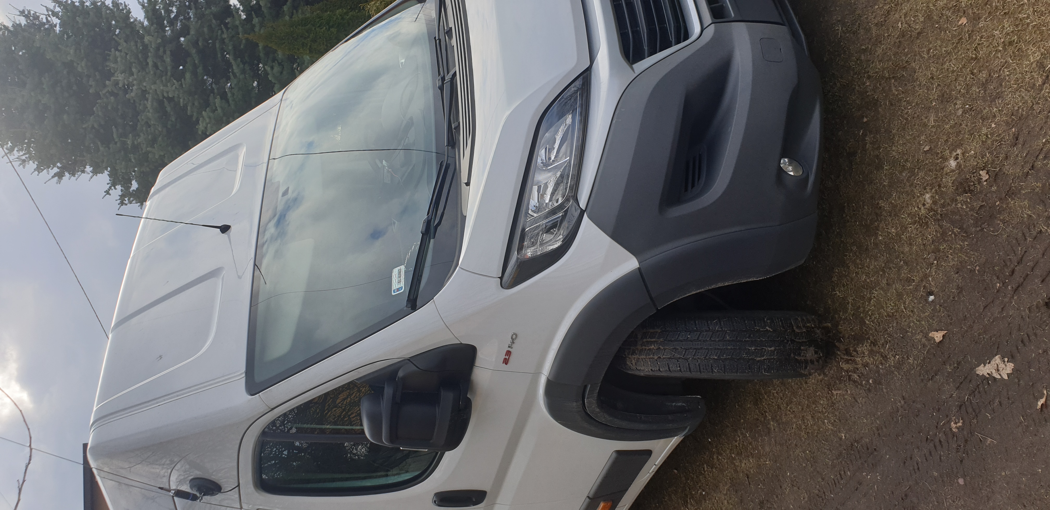 Biały bus marki Fiat Ducato 2.3 JTD zaparkowany na ziemi, widok z przodu z lekkiego ukosa.