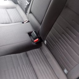 Celina Mieszczakpranie - Szczegółowe ujęcie tylnej kanapy samochodowej z widocznymi pasami bezpieczeństwa, mocowaniem ISOFIX i teksturowaną tapicerką w odcieniach szarości.