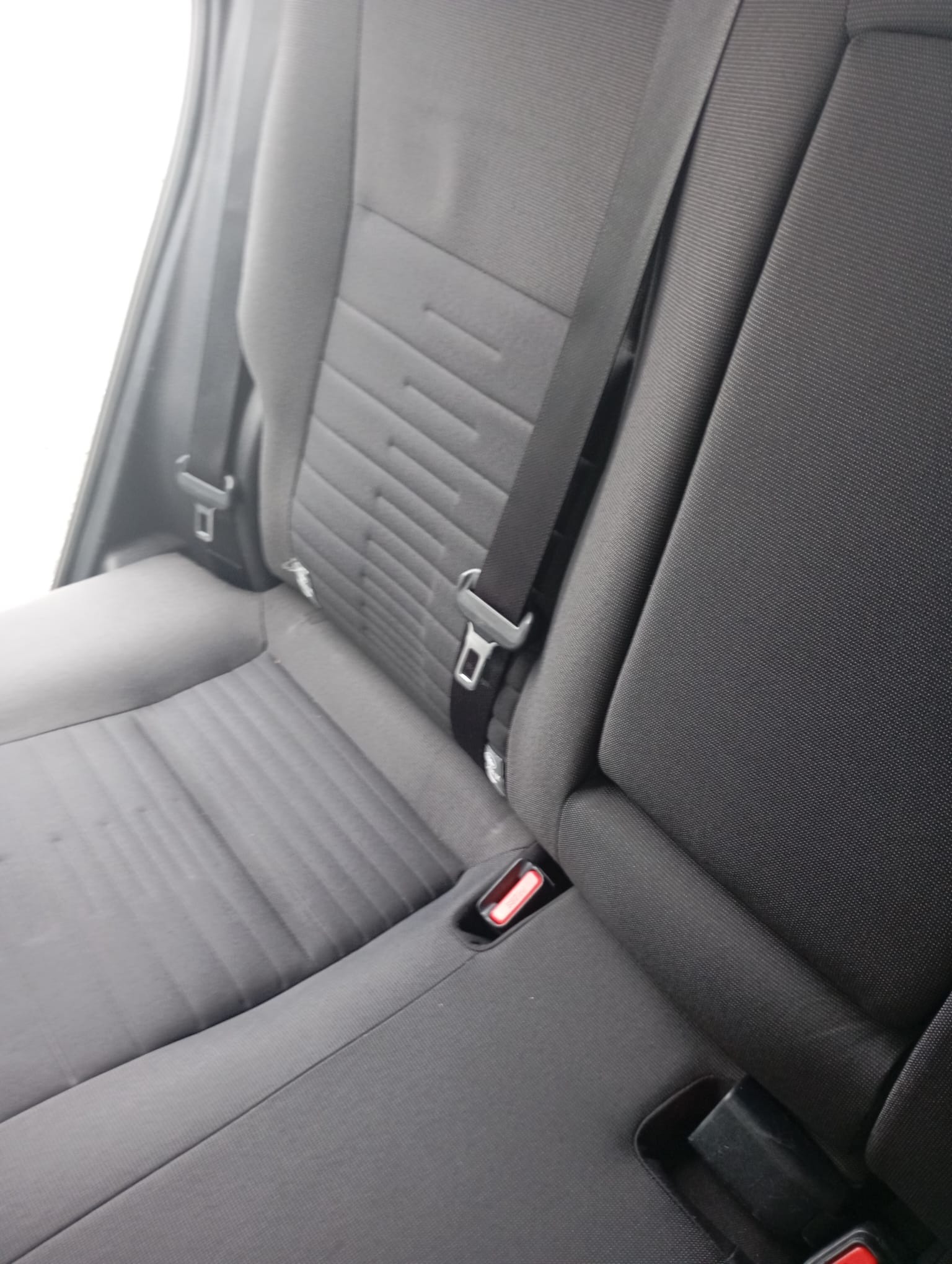 Szare, tekstylne siedzenie samochodowe z pasami bezpieczeństwa, widoczne z bliska. Usługa czyszczenia tapicerki samochodowej w Lyski.