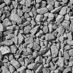 Szary, drobny kamień o nieregularnych kształtach wypełniający całą powierzchnię kadru, oświetlony z góry, tworzący teksturę.