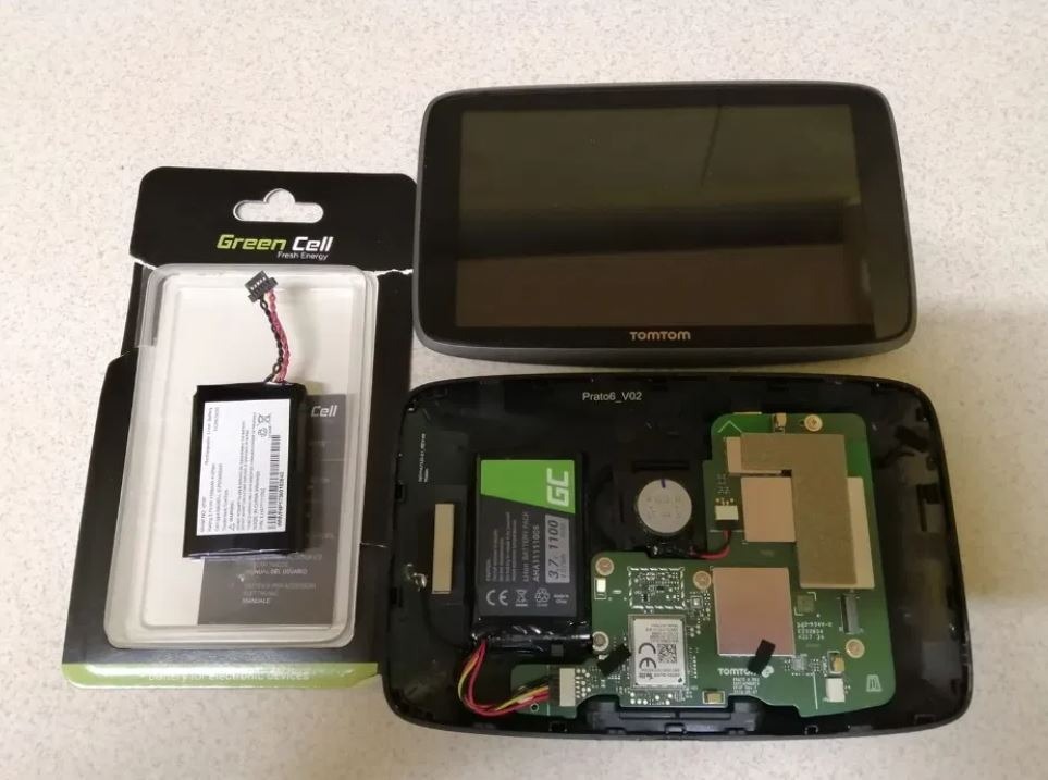 Otwarty GPS TomTom z widoczną elektroniką i baterią Green Cell w opakowaniu, prawdopodobnie podczas wymiany baterii.