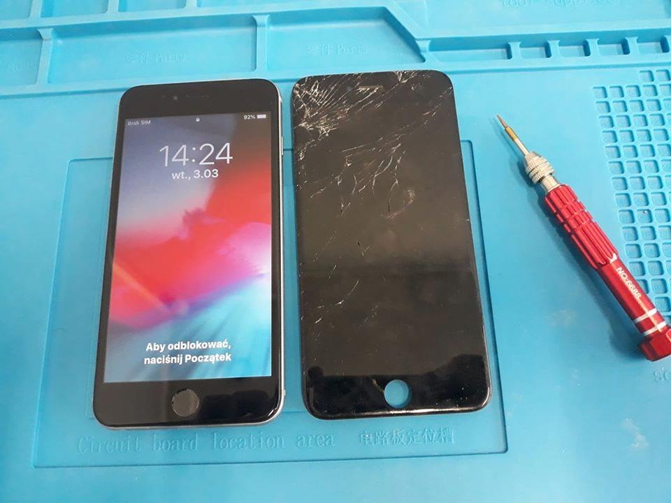 Smartfon z działającym ekranem obok smartfona z pękniętym ekranem, leżące na niebieskiej macie do napraw, obok czerwony śrubokręt precyzyjny.