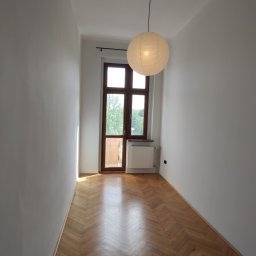 Yaroslav Zakhidnyy - Wnętrze wąskiego pokoju po remoncie z parkietem ułożonym w jodełkę, świeżo pomalowanymi na biało ścianami i papierową lampą wiszącą.