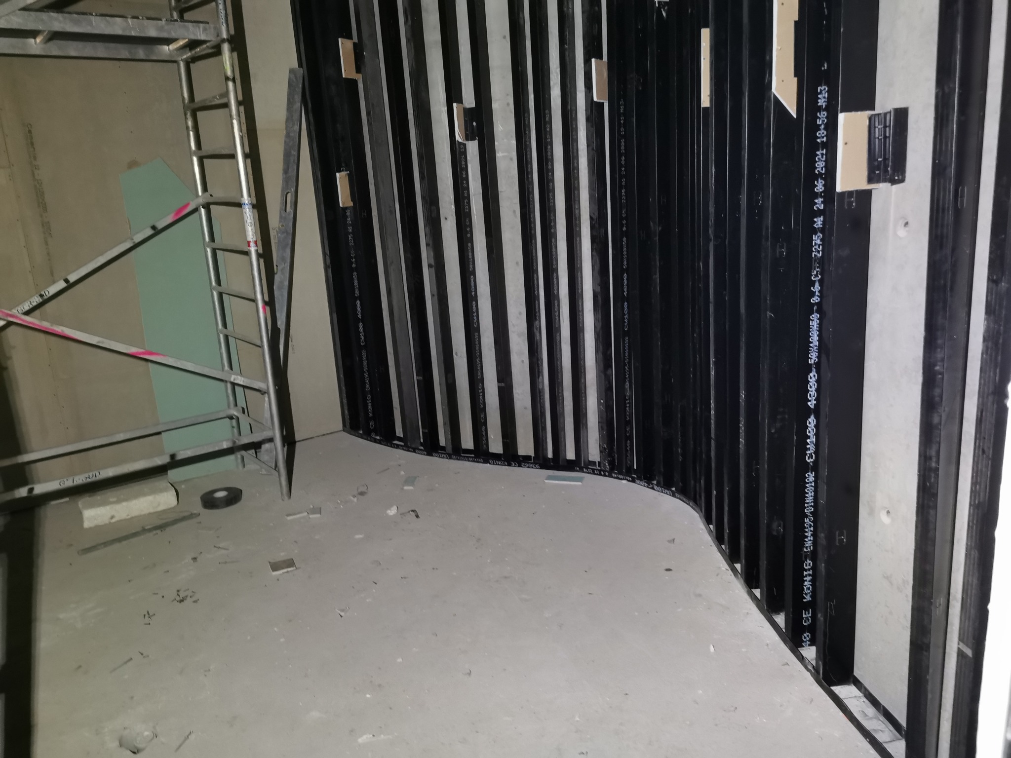 Konstrukcja szkieletowa z profili stalowych przy ścianie z płyt gipsowo-kartonowych, widoczne rusztowanie i poziomica.