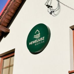 Okrągły podświetlany kaseton dla Heweliusz House. Zdjęcie tuż po montażu w Stegnie. Montaż usprawniła lokalna firma Des-Bud Podnośniki Koszowe ze Sztutowa. 2025