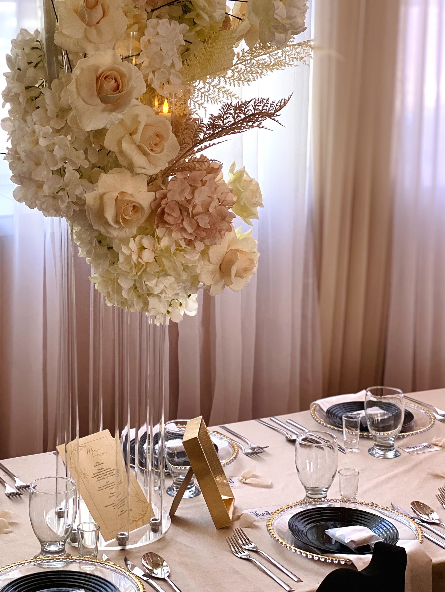 Elegancka dekoracja stołu z kwiatami i menu w Dynowie. Kryształowe wazony, złote akcenty i subtelne oświetlenie tworzą wyrafinowaną atmosferę przyjęcia.
