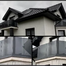 Nowoczesny dom z balkonami zabezpieczonymi szarymi, szklanymi panelami, widok z dołu na elewację w pochmurny dzień.