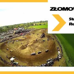 Widok z lotu ptaka na teren złomowiska z torem przeszkód, gdzie odbywa się rywalizacja pojazdów. W tle składowisko aut, a na torze widoczni ludzie i maszyny budowlane.