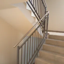 Wewnętrzne schody z betonowymi stopniami i metalową balustradą z poręczą ze stali nierdzewnej, widok z dołu na górę.