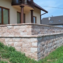 BART-BUD Bartłomiej Gałęziowski - Wykończona obudowa tarasu i schodów wejściowych z kostki łupanej w odcieniach beżu i brązu, na tle domu z balkonem i zieleni. Estetyczne i solidne wykonanie.