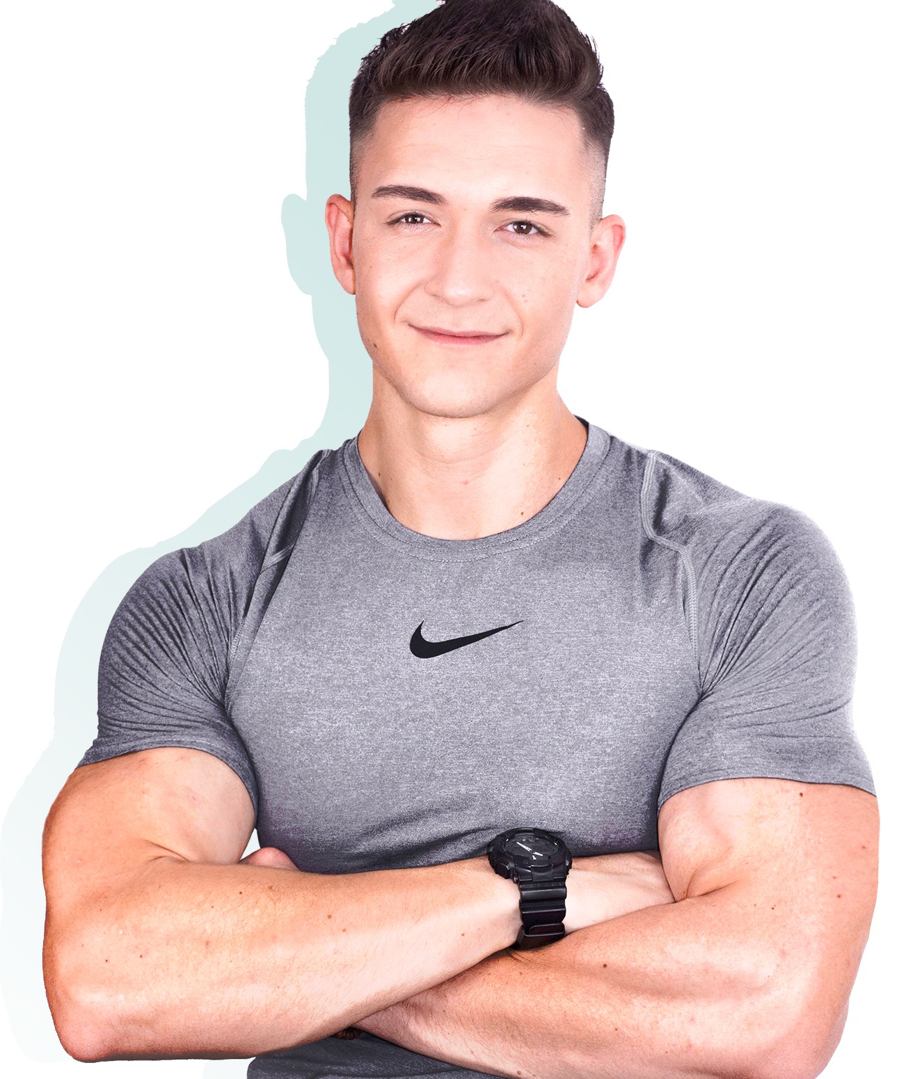 Uśmiechnięty mężczyzna w szarej koszulce sportowej z logo, czarnym zegarkiem na nadgarstku i skrzyżowanymi ramionami na białym tle.