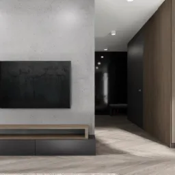 Minimalistyczny salon z betonową ścianą, telewizorem, drewnianą szafką RTV i parkietem w jodełkę; w tle widoczny korytarz z ciemnym wykończeniem.