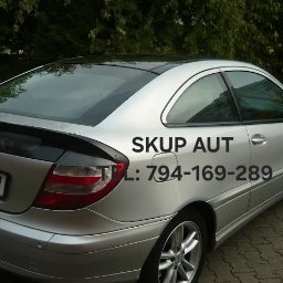 Skup Aut Poznań - Srebrny Mercedes Coupe z czarnym dachem i spojlerem, widoczny numer telefonu do skupu aut nałożony na karoserię, zaparkowany na brukowanej powierzchni.