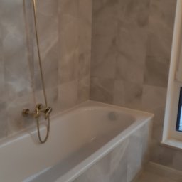 ANATOLII - Wykończona łazienka z wanną obudowaną marmurowymi płytkami, złotą baterią prysznicową i marmurową podłogą