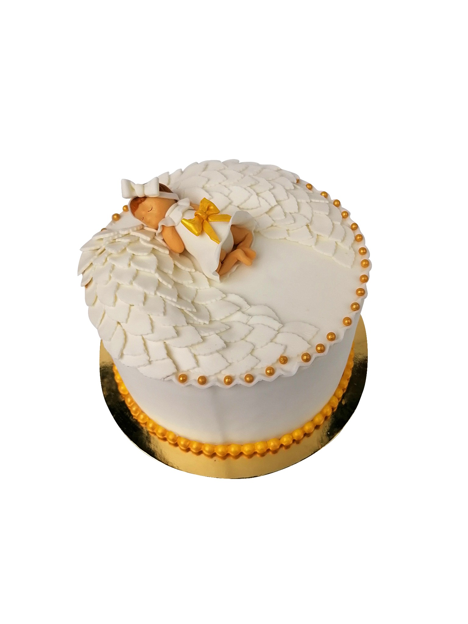 Tort okrągły z dekoracją imitującą skrzydełka anioła i figurką śpiącego dziecka z kokardką, umieszczony na złotej podkładce, z detalami w postaci złotych kuleczek.