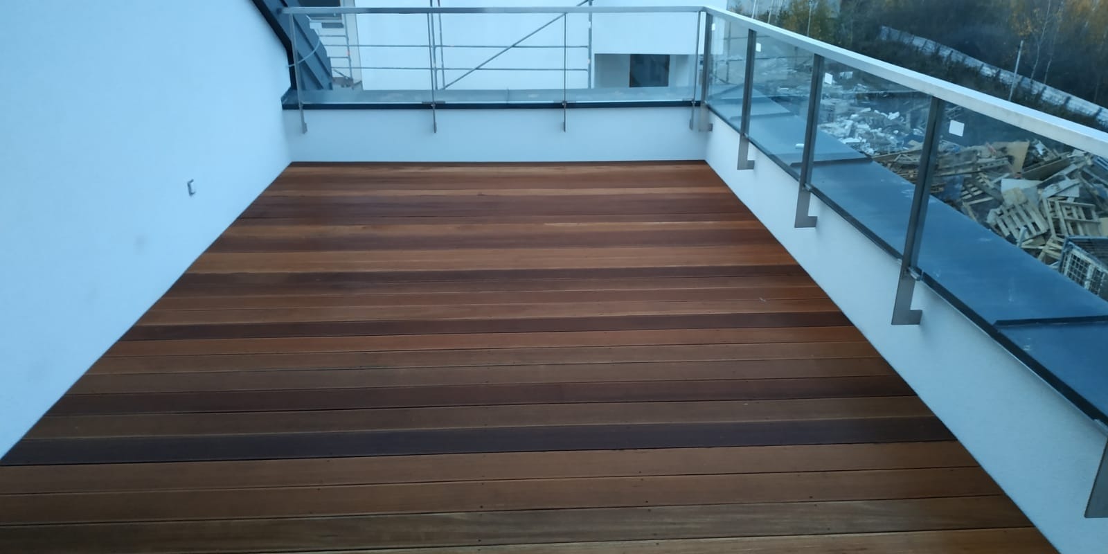 Nowoczesny taras kompozytowy z drewnianą podłogą i szklanymi balustradami w Warszawie, widok z góry na starannie ułożone deski.