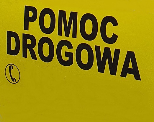Żółte tło z czarnym napisem 'POMOC DROGOWA' i symbolem telefonu w kółku.