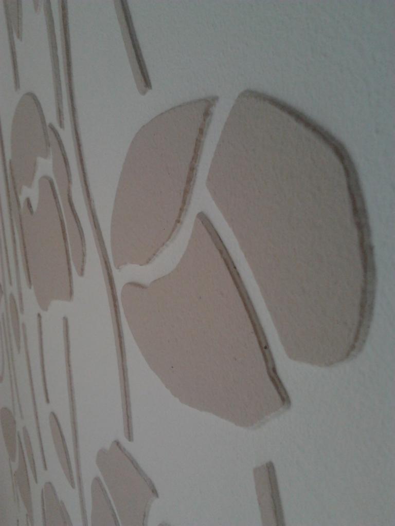 Dekoracyjna ściana z wypukłym wzorem kwiatowym w odcieniach beżu i bieli, widok z boku, ukazujący fakturę i trójwymiarowość zdobienia.