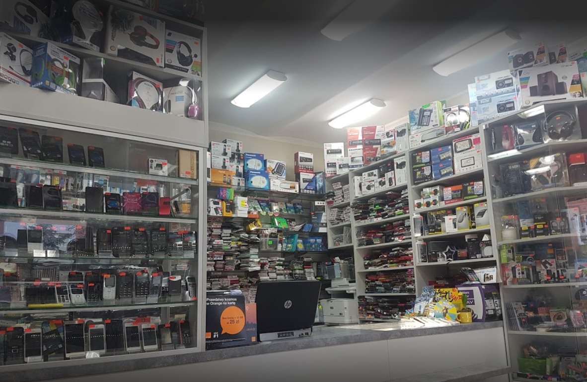 Wnętrze sklepu z elektroniką: półki uginają się pod ciężarem telefonów komórkowych, słuchawek, radioodtwarzaczy i akcesoriów, z laptopem HP na pierwszym planie.