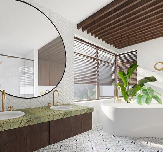 Nowoczesna łazienka z zielonym blatem umywalki, okrągłym lustrem z czarną ramą, białym wolnostojącym wanną i drewnianą żaluzją okienną.