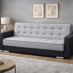 Bersky - Rozkładana sofa z szarym, pikowanym siedziskiem i czarnymi bokami, na tle szarej ściany z obrazami. Na pierwszym planie stolik kawowy i dywan.