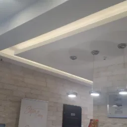 Nowoczesne oświetlenie sufitowe z podwieszanym sufitem i trzema okrągłymi lampami wiszącymi na tle ściany wyłożonej dekoracyjną okładziną.