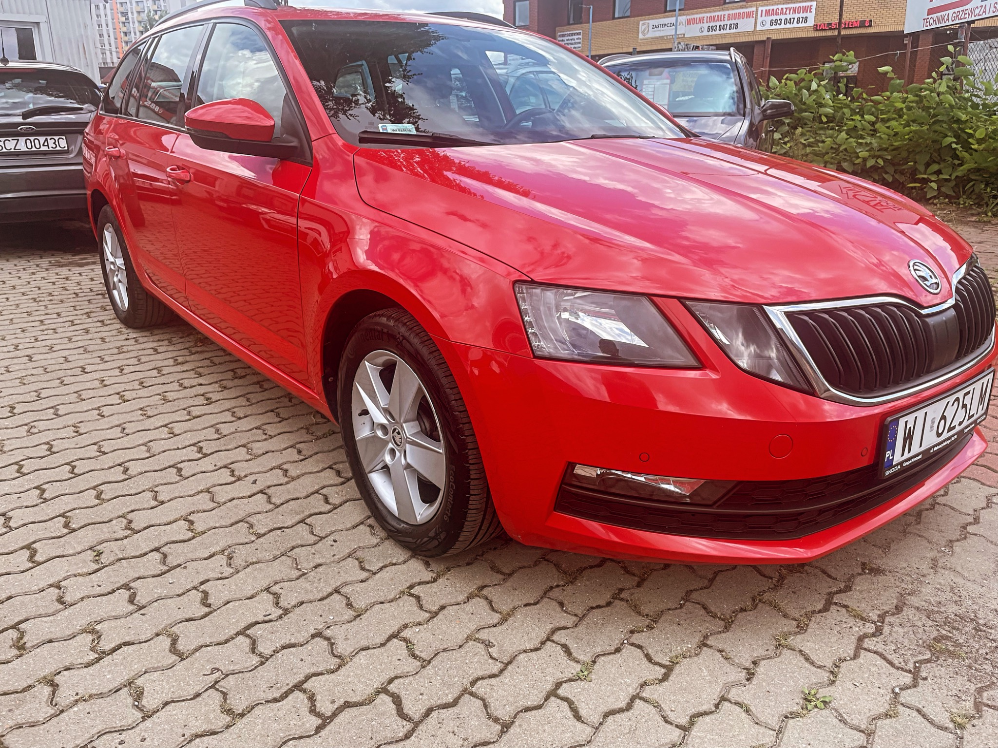 Czerwona Skoda Octavia Combi zaparkowana na kostce brukowej, widok z przodu na zewnątrz, z widocznymi tablicami rejestracyjnymi.
