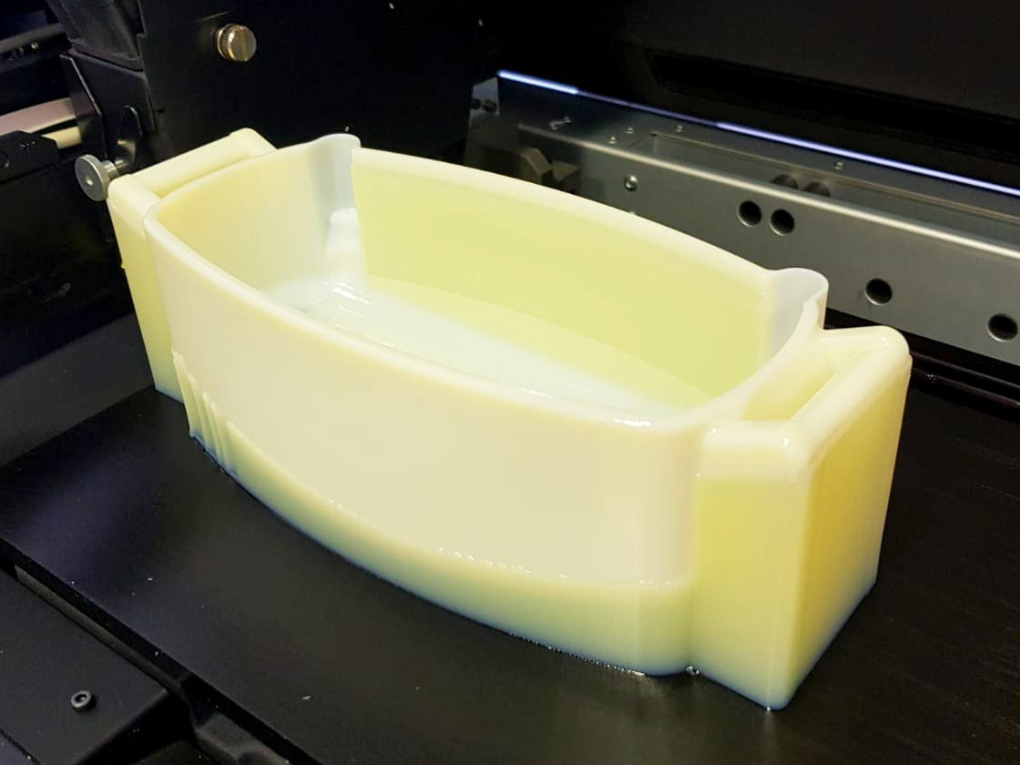 Jasny, trójwymiarowy model w kształcie wanny, wykonany z tworzywa sztucznego, umieszczony wewnątrz drukarki 3D.