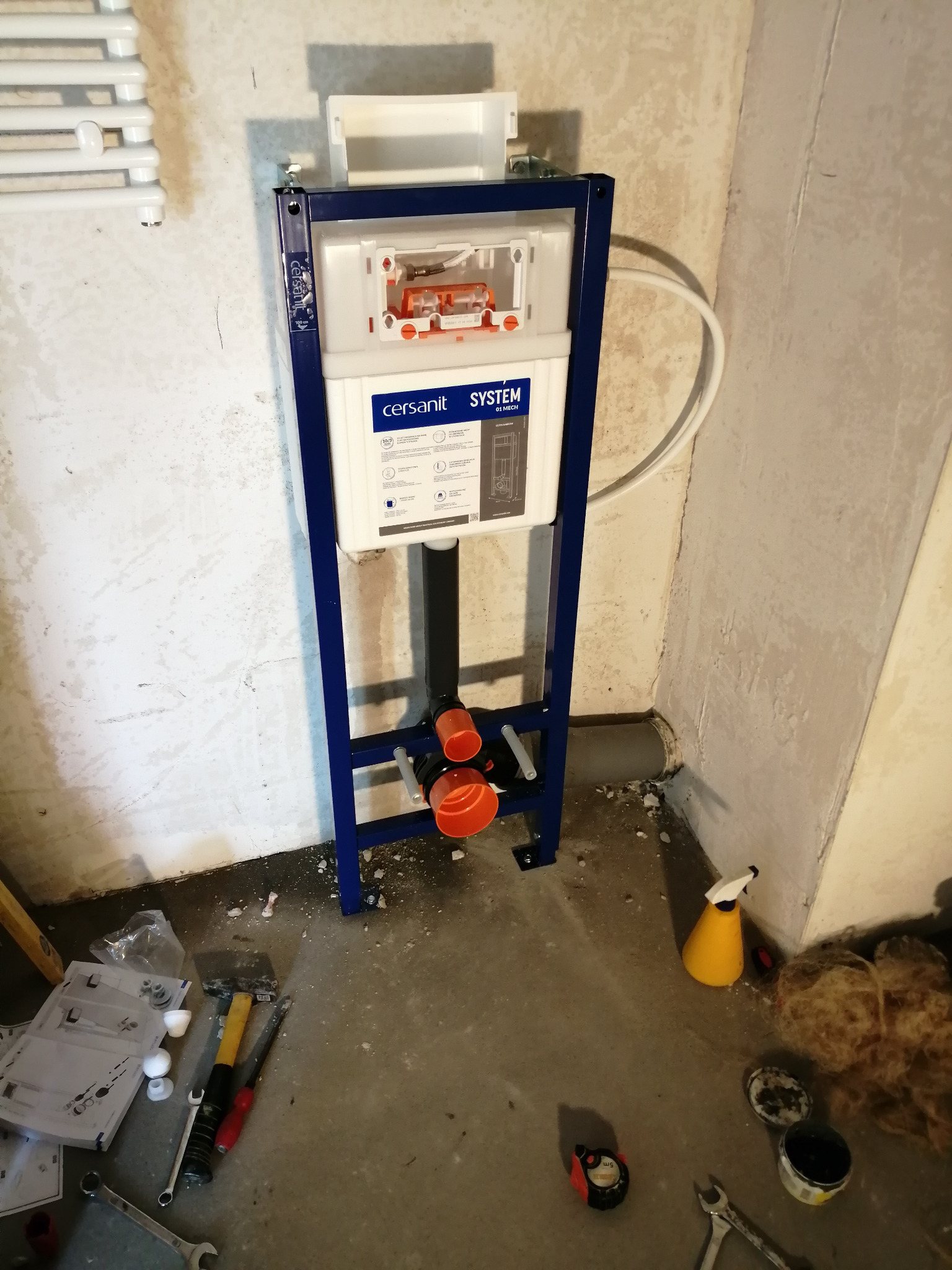 Stelaż podtynkowy Cersanit zamontowany przy ścianie w trakcie instalacji, widoczne narzędzia i akcesoria hydrauliczne na podłodze.