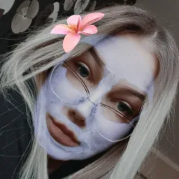 Portret kobiety z blond włosami i okularami, z nałożoną na twarz maseczką kosmetyczną i filtrem kwiatowym.