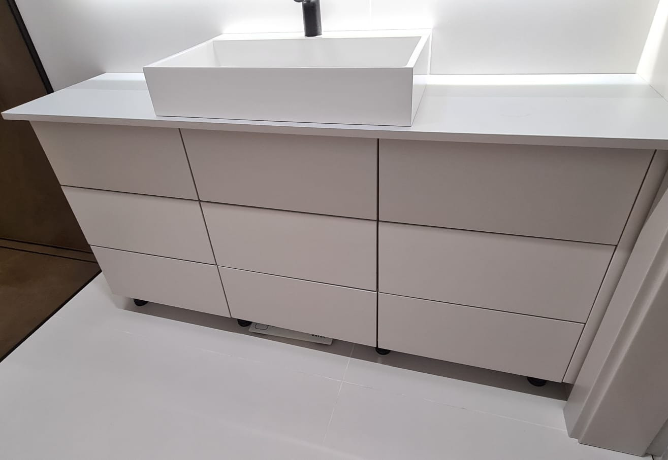 Nowoczesna, biała szafka łazienkowa z umywalką nablatową i czarną armaturą. Minimalistyczny design, gładkie fronty szuflad, białe płytki podłogowe.