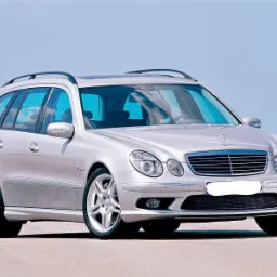 Srebrny Mercedes-Benz klasy E kombi, widok z przodu, na tle błękitnego nieba.