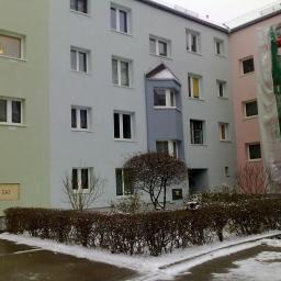 P.H.Krzysztof paludkiewicz - Wielobarwny budynek wielorodzinny z oknami, częściowo ośnieżony, z widocznymi rusztowaniami i siatką ochronną przy jednej ze ścian.