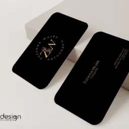 Dwie czarne wizytówki z zaokrąglonymi rogami, złote napisy i logo 'ZW' w okręgu z liśćmi, adres i nazwa 'Zuzanna Wujek Fotografia' na jasnym tle.