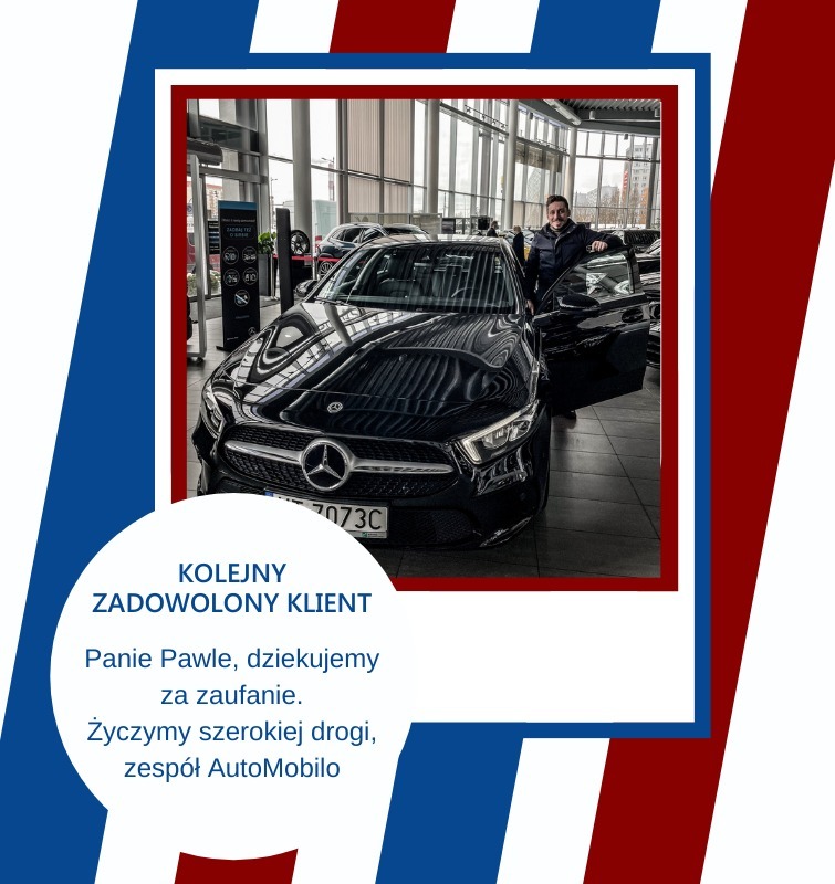 Czarny samochód osobowy marki Mercedes z otwartymi drzwiami, obok którego stoi uśmiechnięty mężczyzna. W tle salon samochodowy z widocznymi innymi pojazdami i ścianą okien.