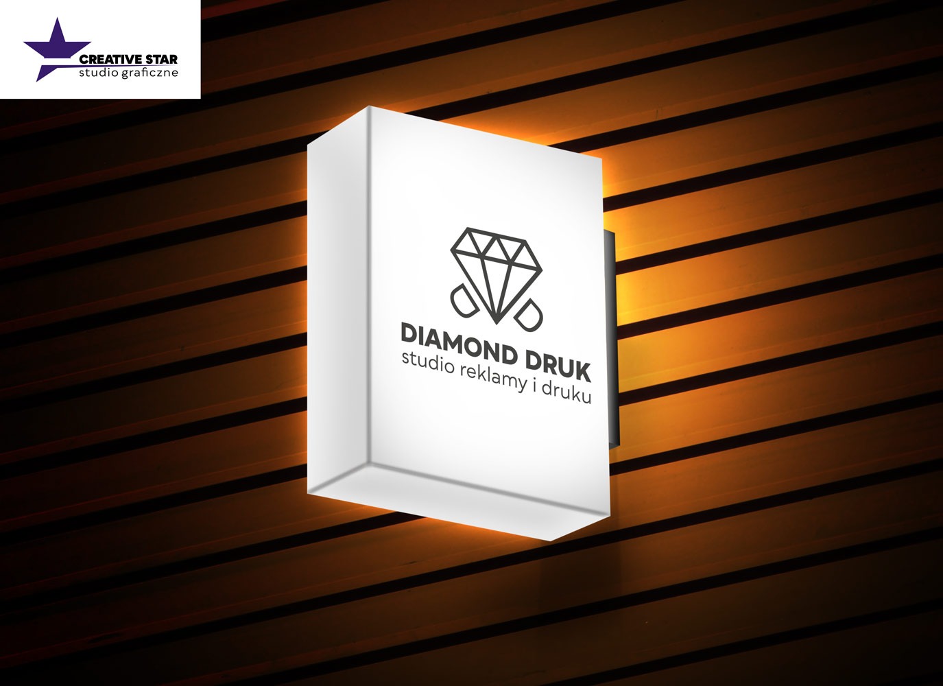 Podświetlany szyld reklamowy z logo i napisem 'Diamond Druk studio reklamy i druku', zamontowany na drewnianej ścianie z poziomymi listwami, oświetlony od tyłu ciepłym światłem.