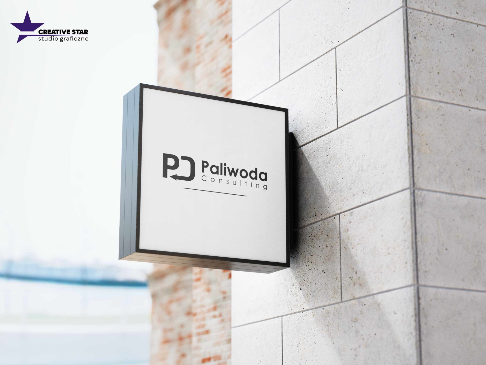 Szyld reklamowy z logo 'PJ Paliwoda Consulting' zamontowany na szarej, teksturowanej ścianie z elementami cegły w tle.