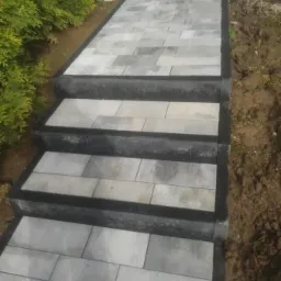 Schody i ścieżka z szarej kostki brukowej prowadzące przez ogród, widok z góry.