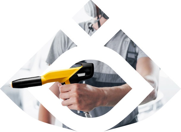 Operator w kombinezonie ochronnym trzyma żółto-czarny pistolet do nanoszenia farby proszkowej, widoczny przewód doprowadzający powietrze.