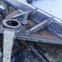 Hard Stal - Metalowa konstrukcja spawana z widocznymi śladami spawania, śrubą i młotkiem w tle, na zewnątrz w zimowych warunkach.