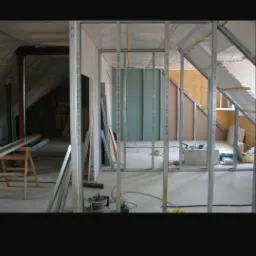 Konstrukcja szkieletowa z profili stalowych do montażu płyt kartonowo-gipsowych w poddaszu, widoczne izolacja i narzędzia budowlane.